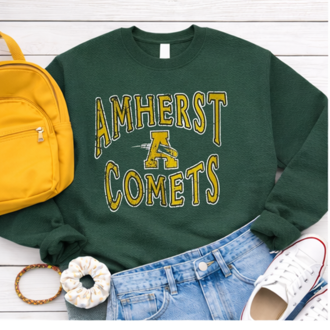 Green sweatshirt with 'Amherst Comets' text, yellow backpack, blue jeans, white sneakers, and scrunchie on a light wooden surface.