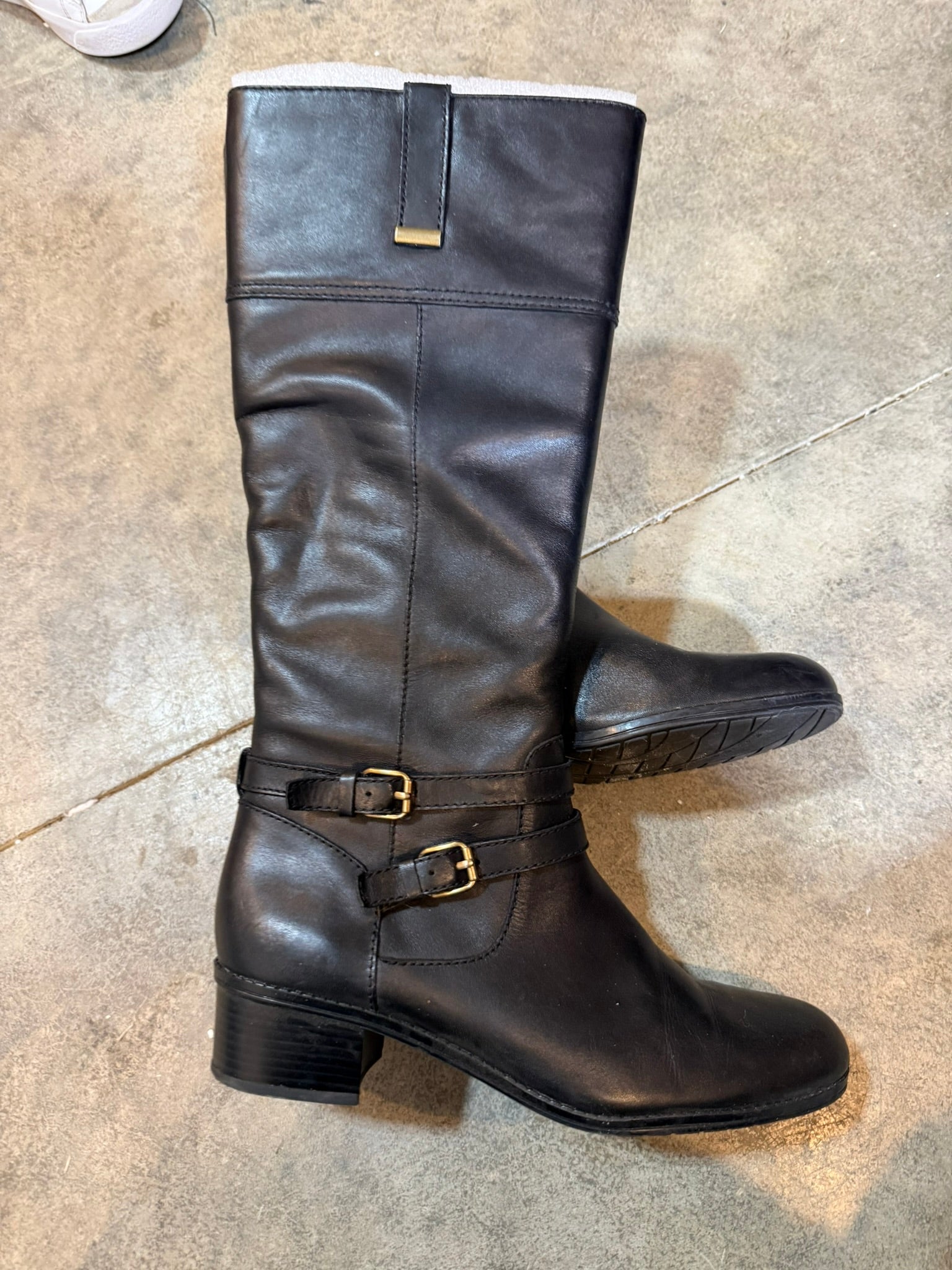 Black leather boot with a buckle on a concrete floor