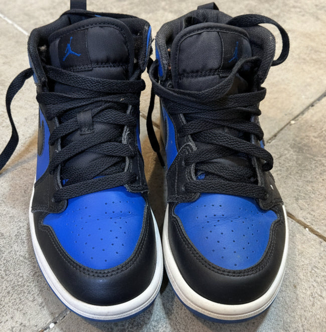 Pair of black and blue high-top sneakers on a concrete floor.
