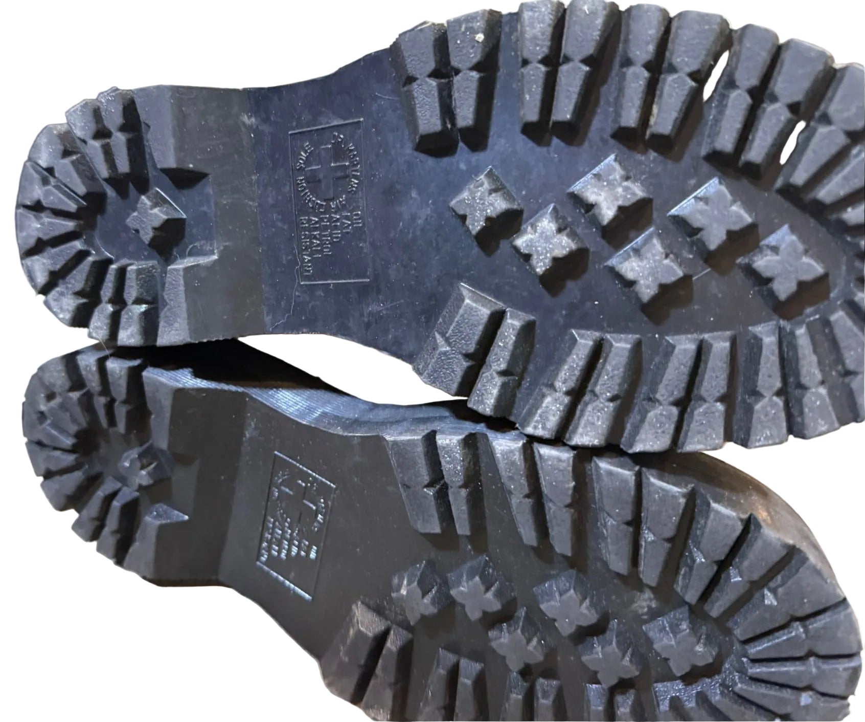Close-up of black boot soles with tread pattern on a blurred background